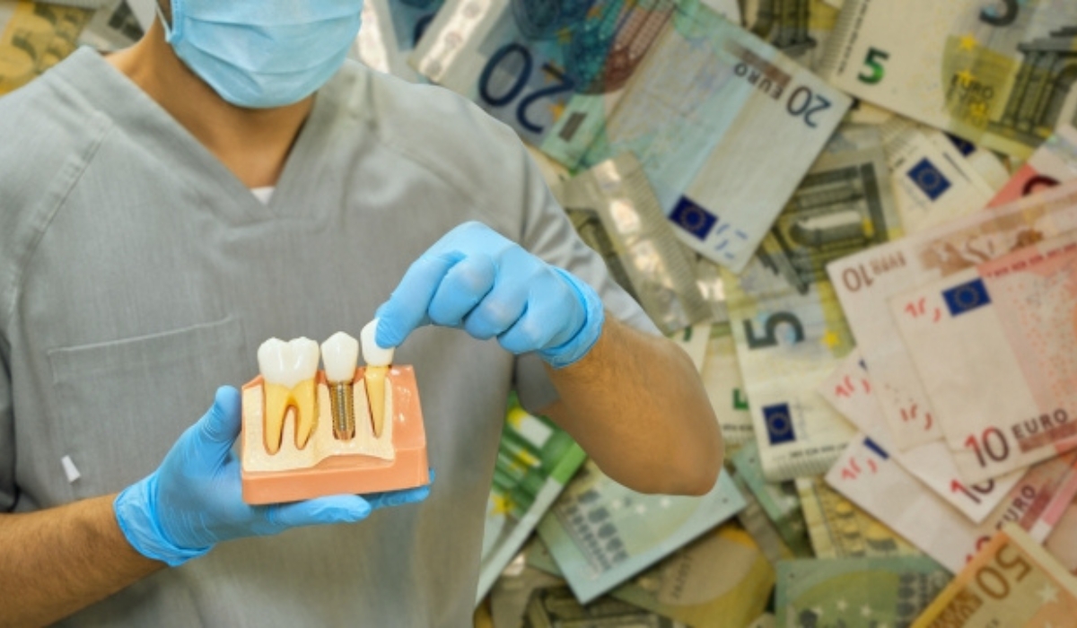 Stomatolog u rukavicama drži model zubnog implantata ispred pozadine sa euro novčanicama