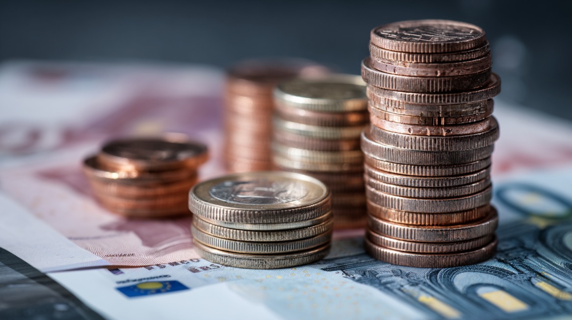 Stogovi evro kovanica složeni na papirnim novčanicama