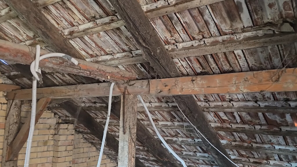 Stare drvene grede na tavanu sa vidljivim tragovima vlage i propadanja